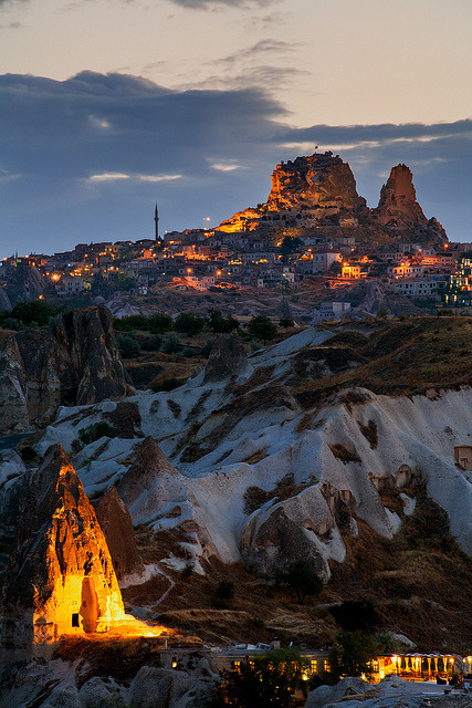 The otherworldly homes in Goreme glow under spotlights during summer twilight, Cappadocia, Turkey